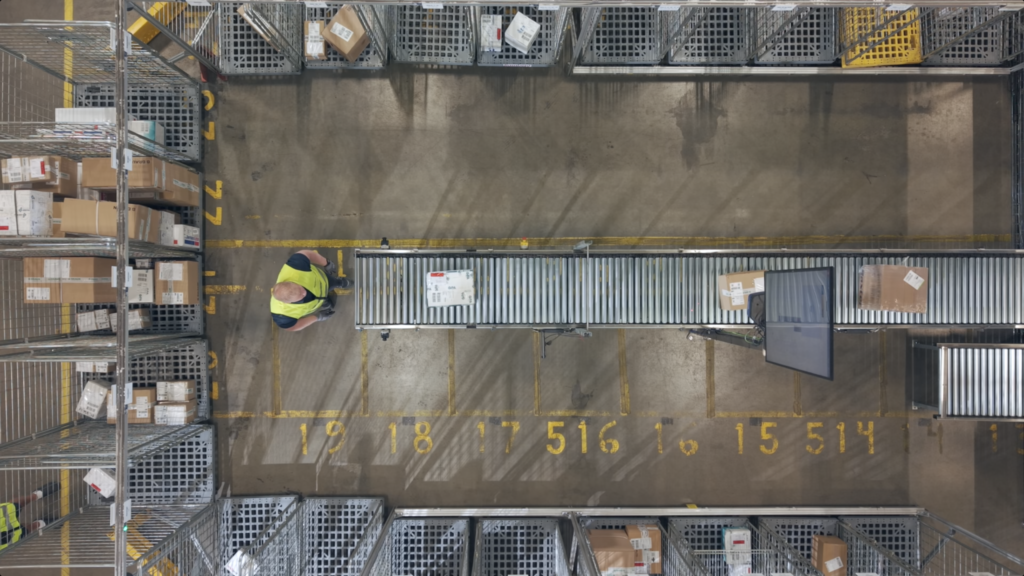 A birdsview image of the Ramberg warehouse with a conveyor belt and a working waiting for a package.