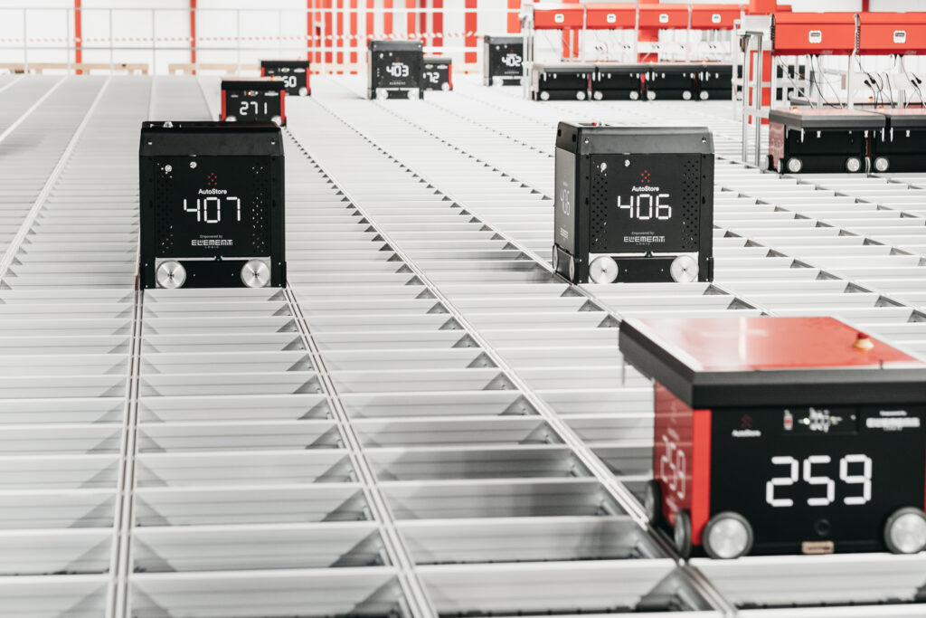 Robots rojos AutoStore desplazándose por encima de una rejilla de aluminio