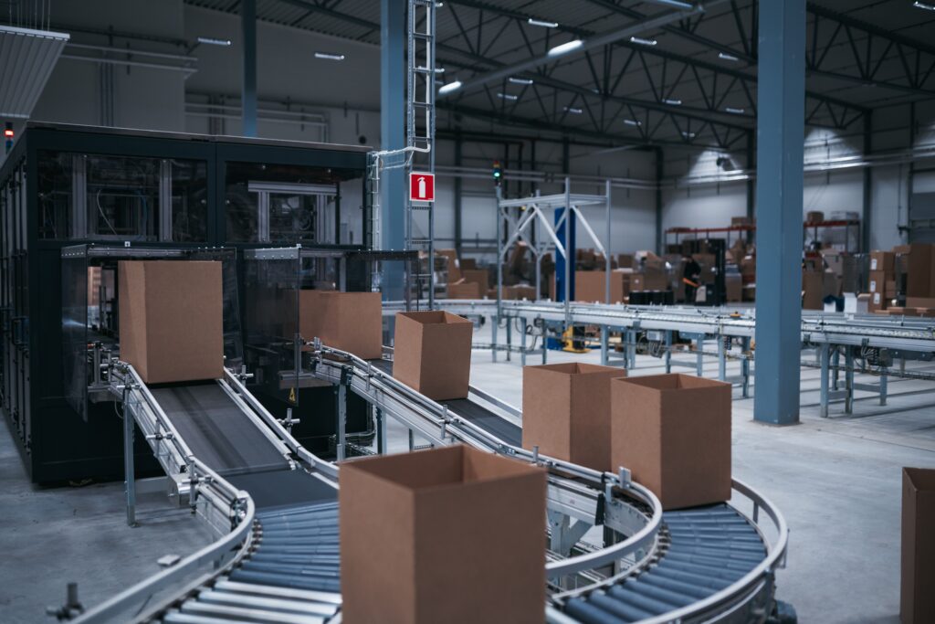 Cajas avanzando por un circuito de cintas transportadoras en una instalación logística automatizada