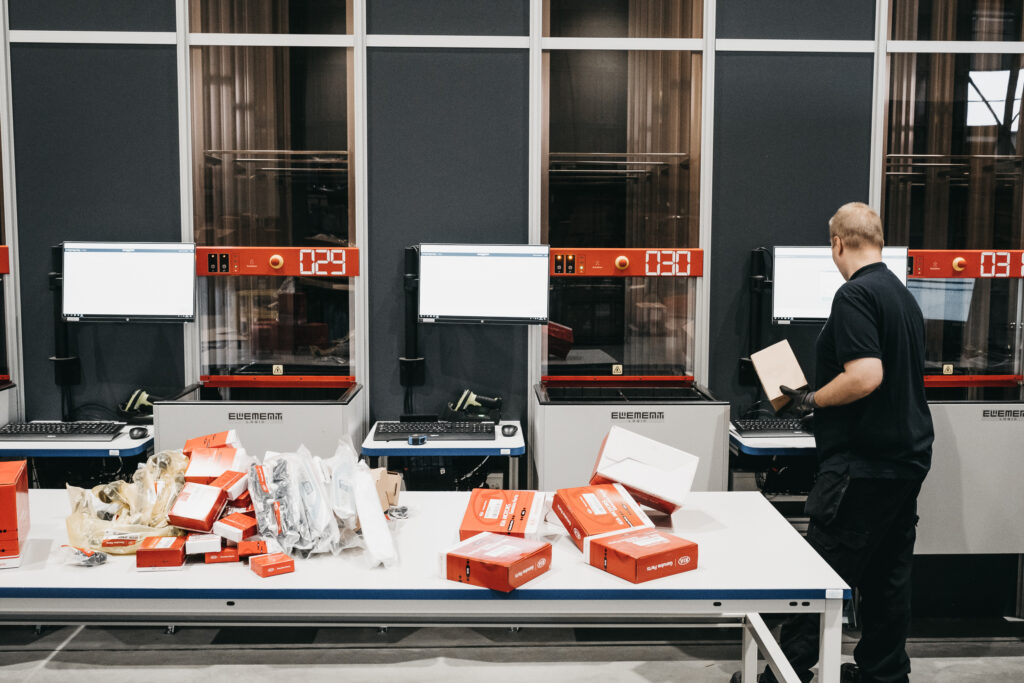 Cubeta de AutoStore con separadores y productos pequeños organizados en un puesto de picking.