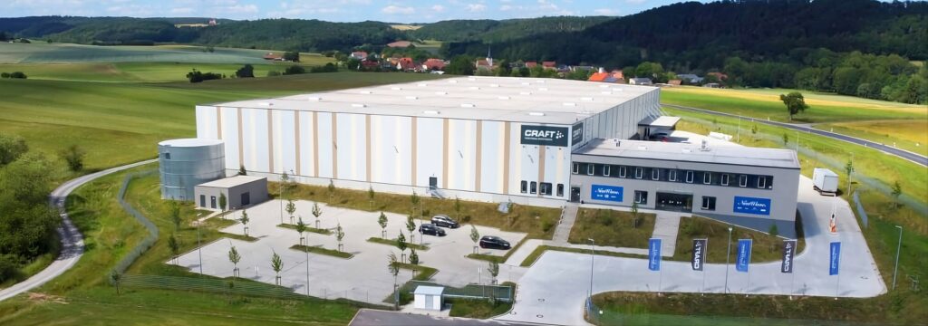 Vista aérea del centro logístico de New Wave en Geiselwind (Alemania), con el edificio principal y el entorno rural.