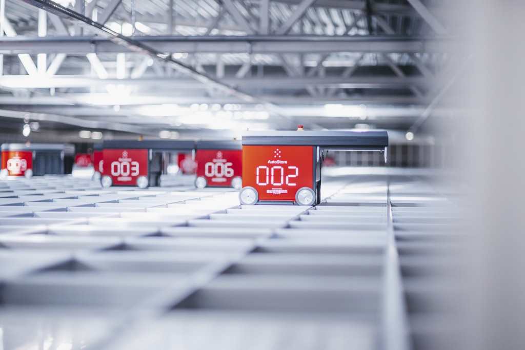 Red AutoStore warehouse automation robots picks orders on a grid.