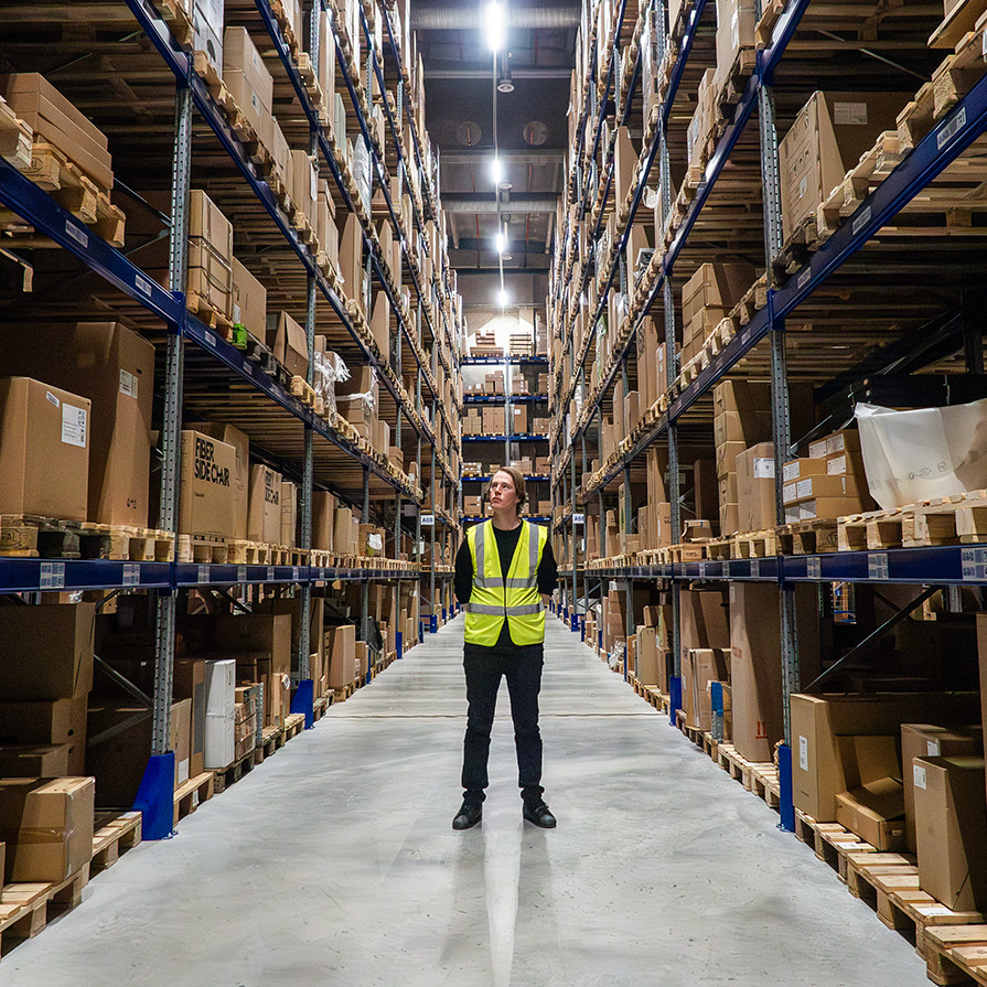 Person standing in a warehouse with shelves on each side